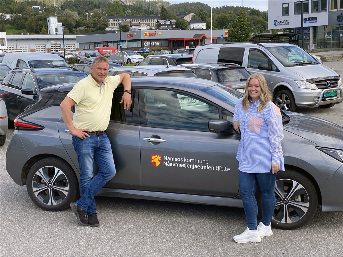 Mann og kvinne poserer foran bil med Namsos kommunes logo. - Klikk for stort bilde