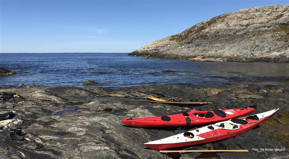 To røde kajakker ligger på land ved sjøen på Aglen, Otterøya - Klikk for stort bilde