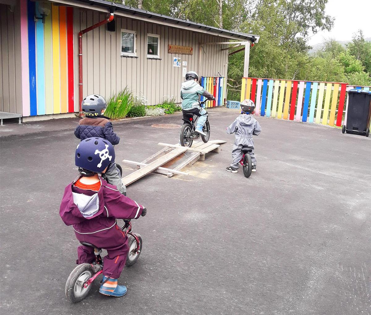 Fire barn som sykler på barnehagens uteområde. - Klikk for stort bilde