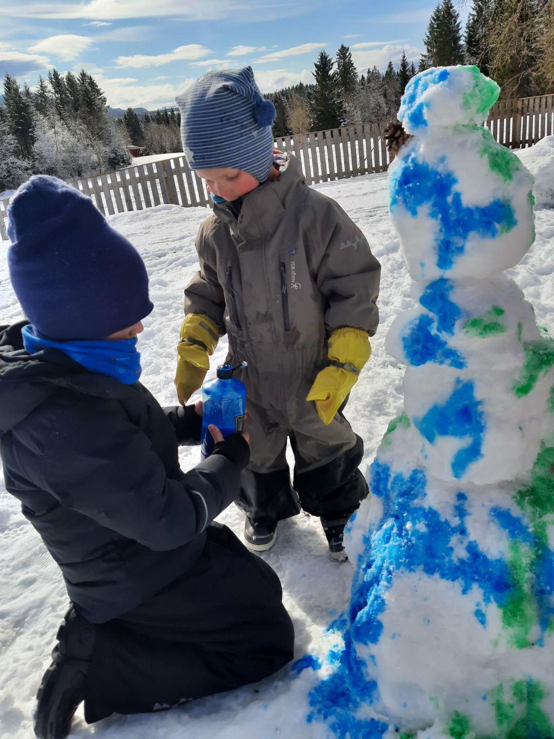 Barnehagebarn lager snømann og farger den grønn og blå - Klikk for stort bilde