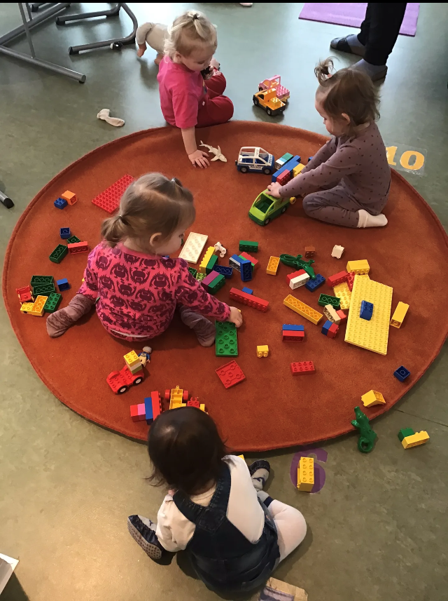 Fire barn som sitter på gulvet og leker med lego. - Klikk for stort bilde