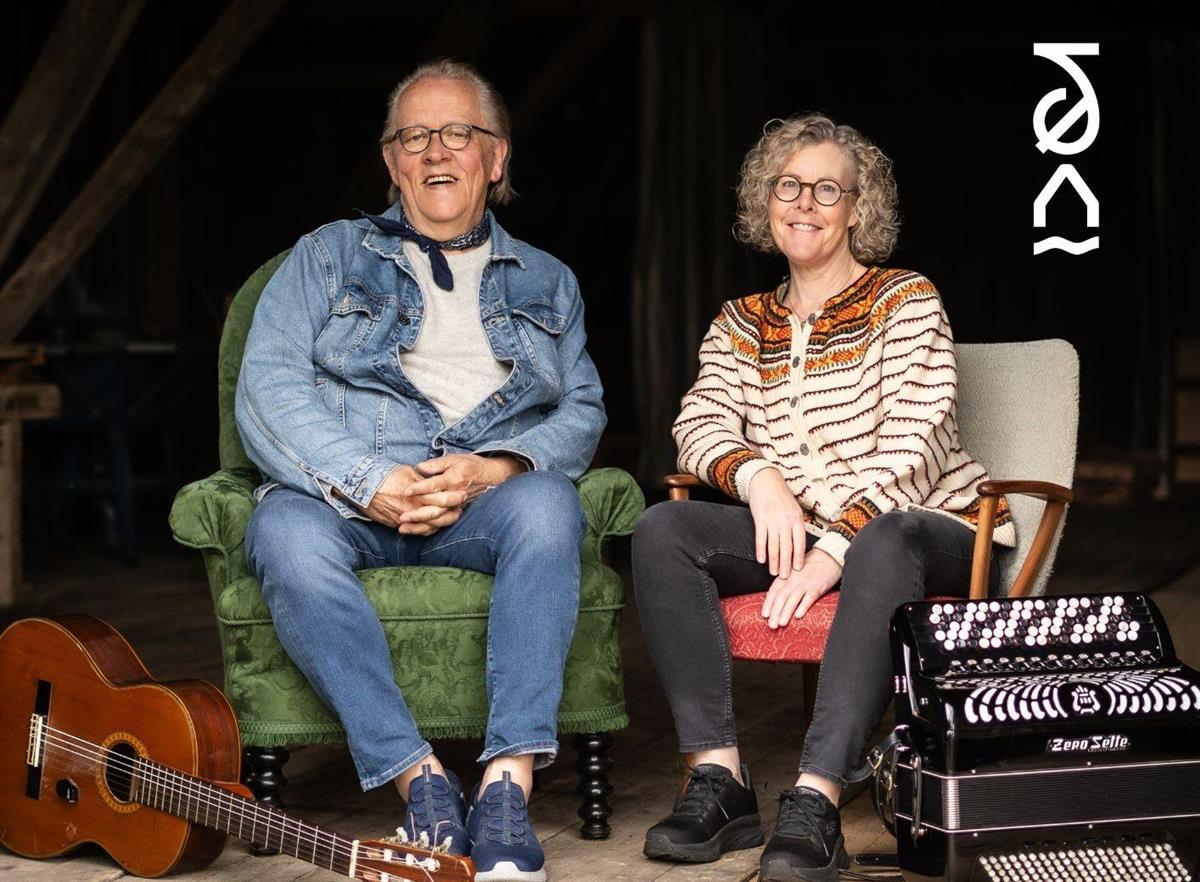 Mann og dame som sitter i hver sin stol med gitar og trekkspill ved sin side - Klikk for stort bilde